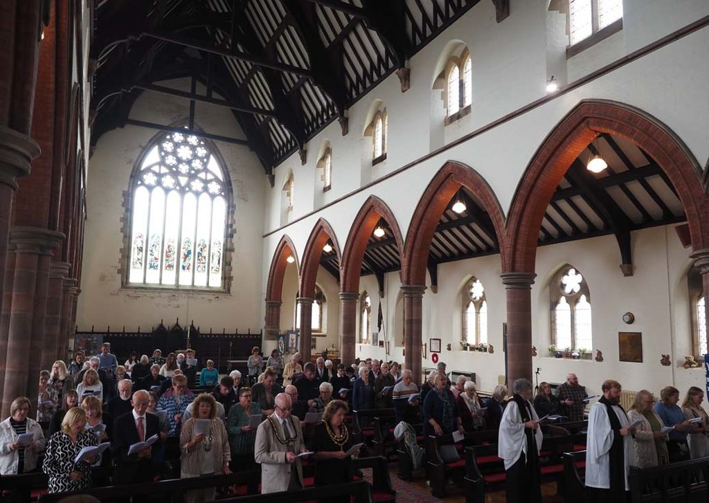 Congregation singing hymn early in the licensing service looking to the West window from the reading lectern.